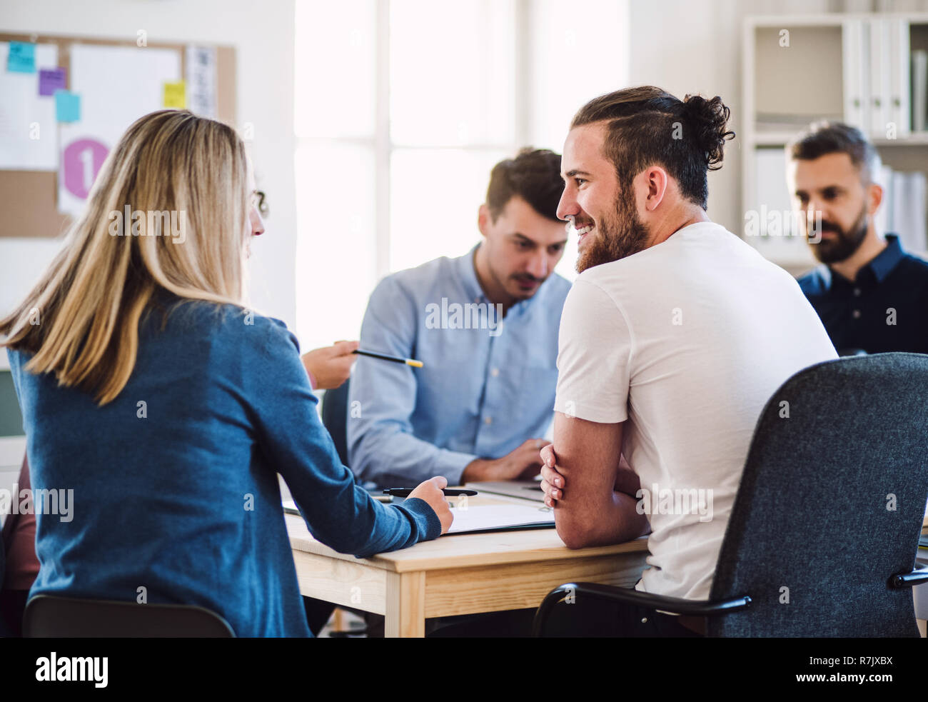 Group of young businesspeople sitting around table in a modern office ...