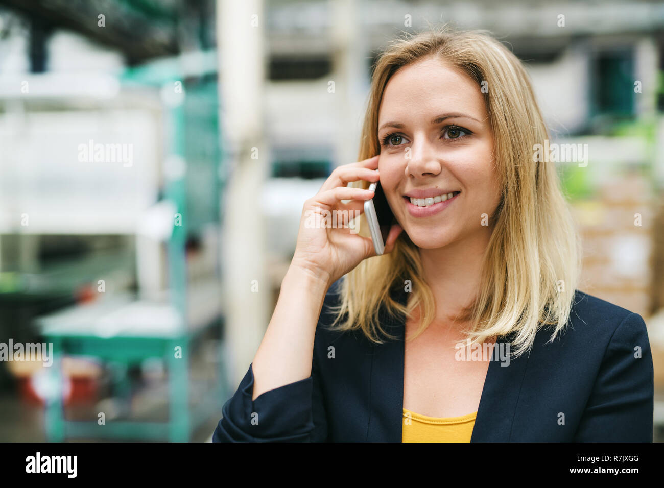 A portrait of an industrial woman engineer on the phone, standing in a factory. Stock Photo