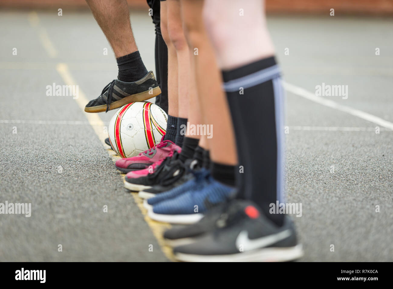 Teenaged schoolboys playing football outside in a UK school Stock Photo