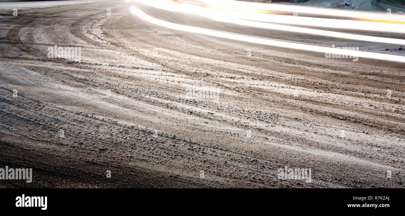 City street intersection covered with snow and dirty tyre tire tracks and light trails in winter night ,  panoramic background Stock Photo