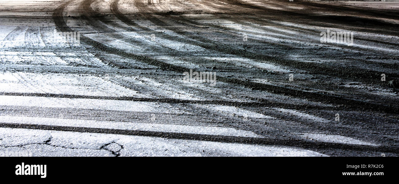 Blurry city street intersection covered with snow and dirty tyre tire tracks in winter night ,  panoramic background Stock Photo