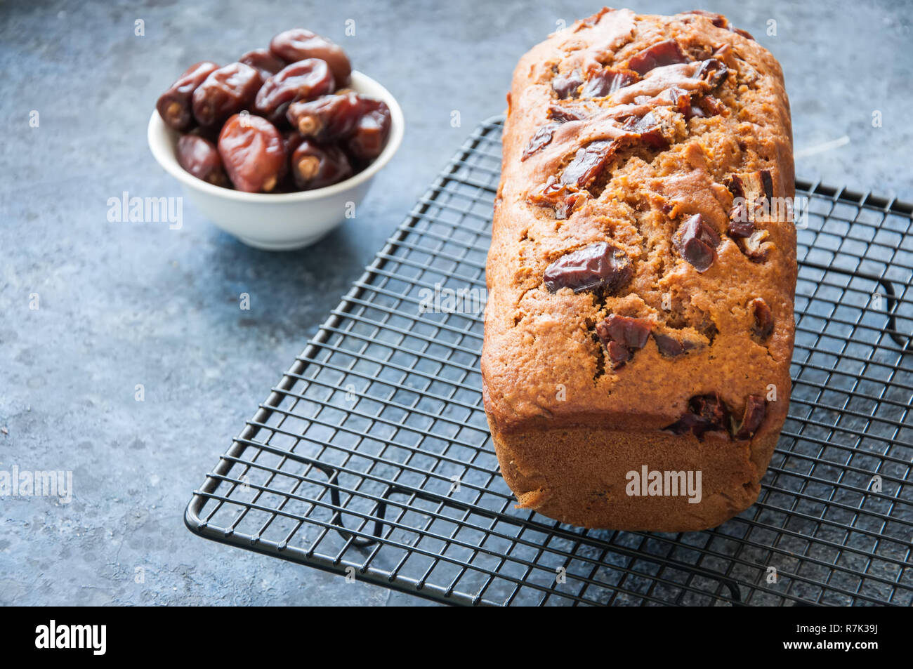 Honey and date spicy cake serving on a wire rack. Blue stone bac Stock
