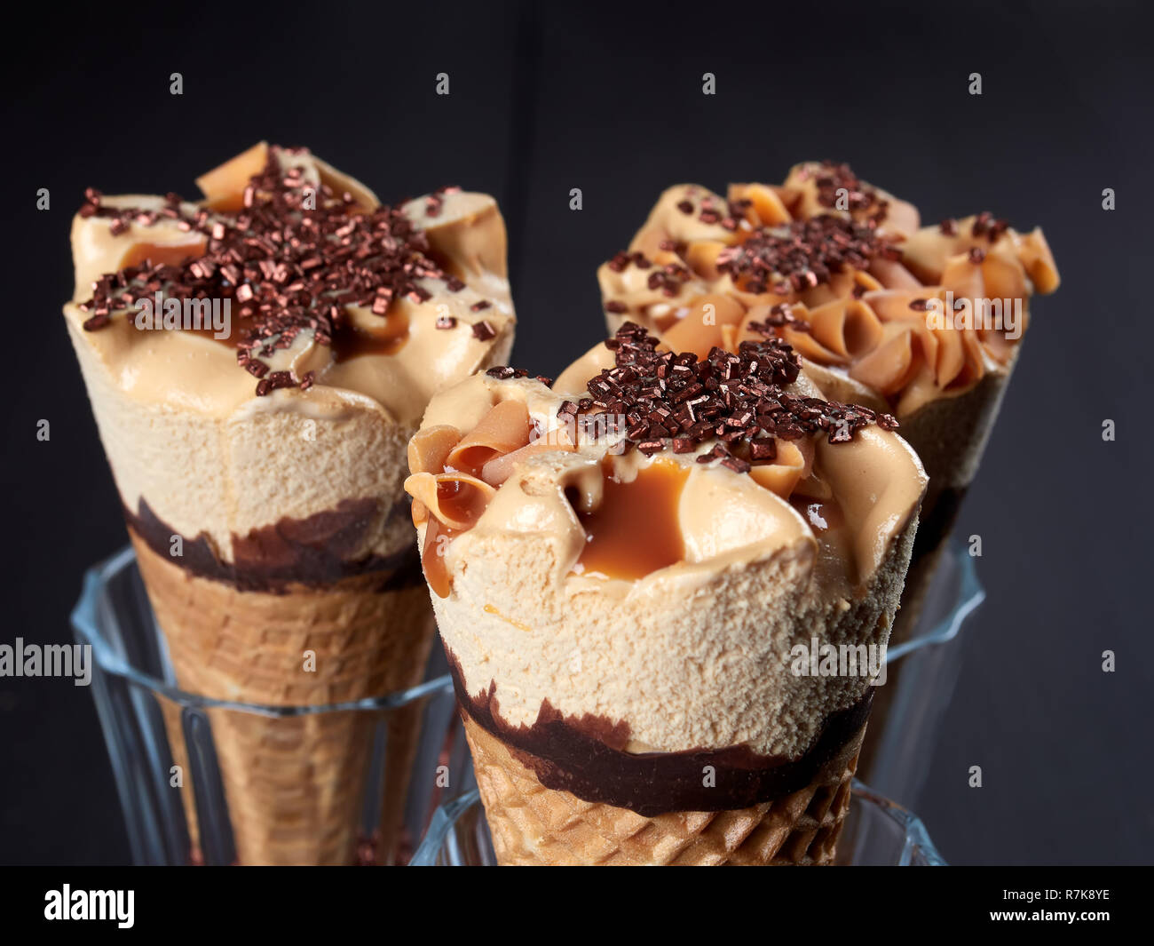 Three caramel ice cream cones, set in glasses filled with sugar