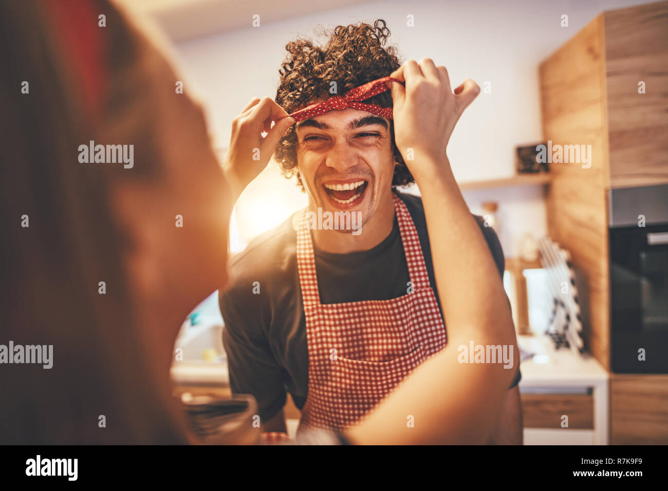 Happy father and his daughter enjoy and having fun in making and having healthy meal together at their home kitchen. The girl binds the ribbon around  Stock Photo