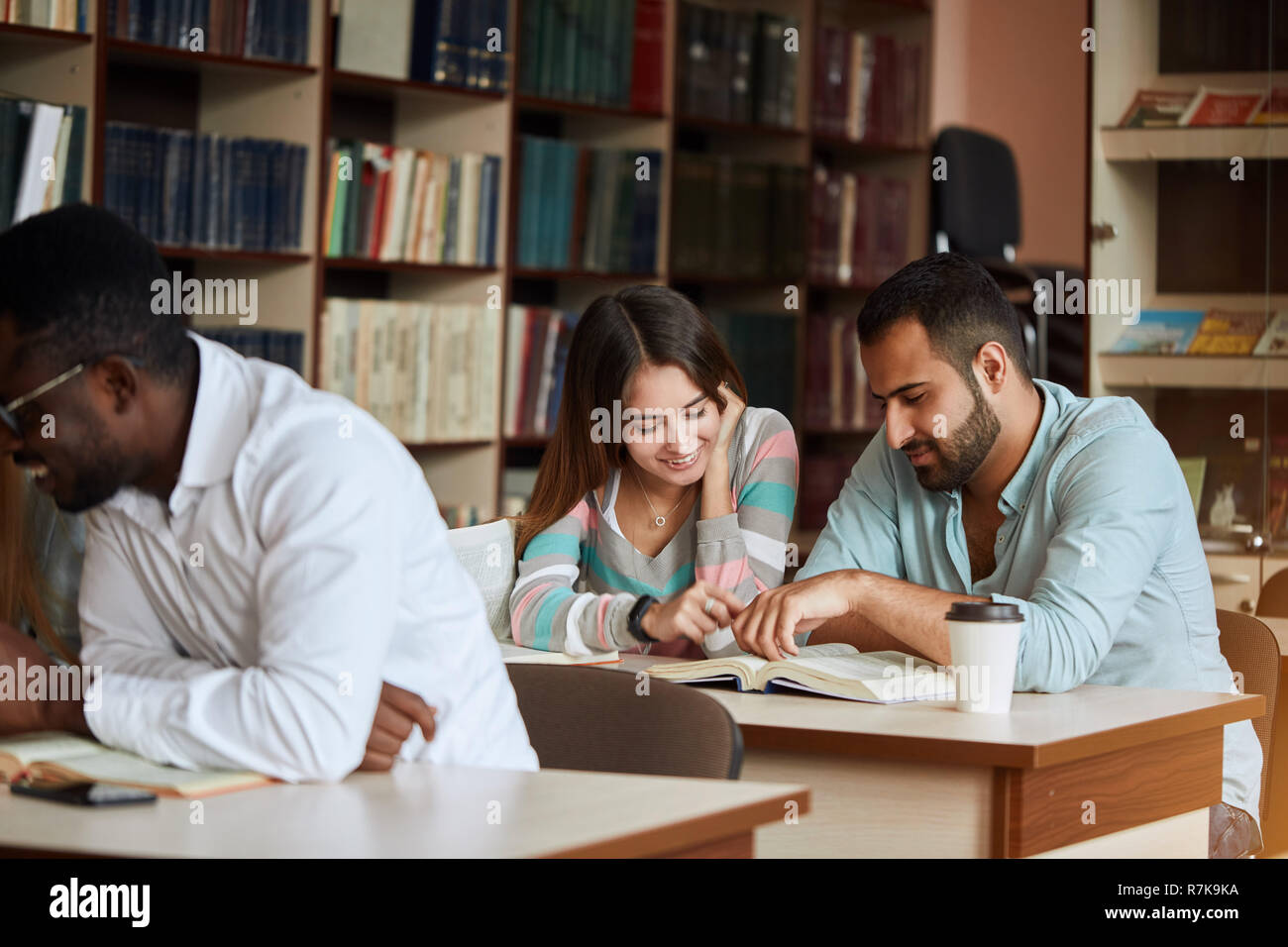group of happy students reading books and preparing to exam in library ...
