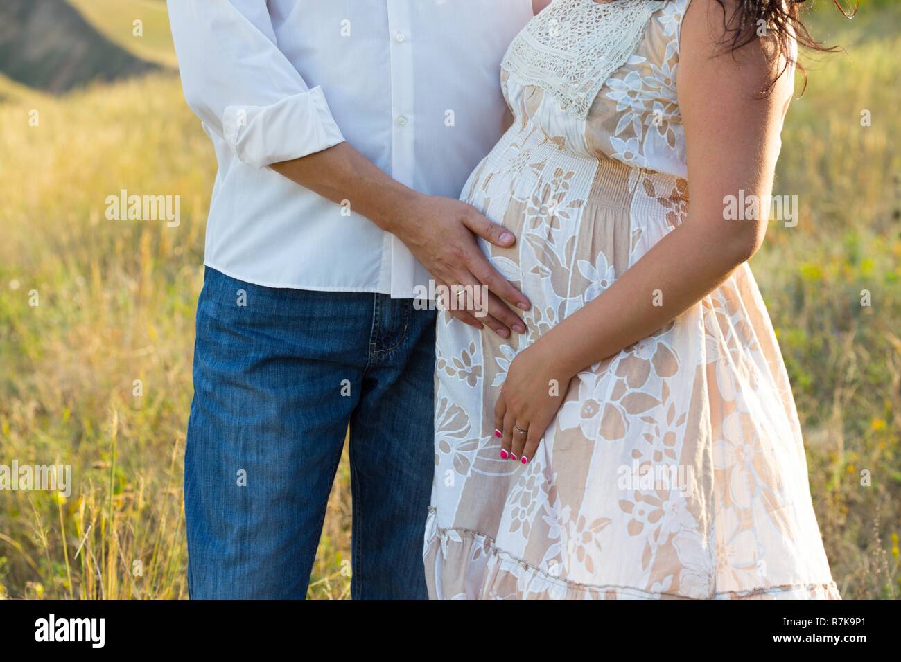 pregnancy a man put his hand on his wife's pregnant belly Stock Photo