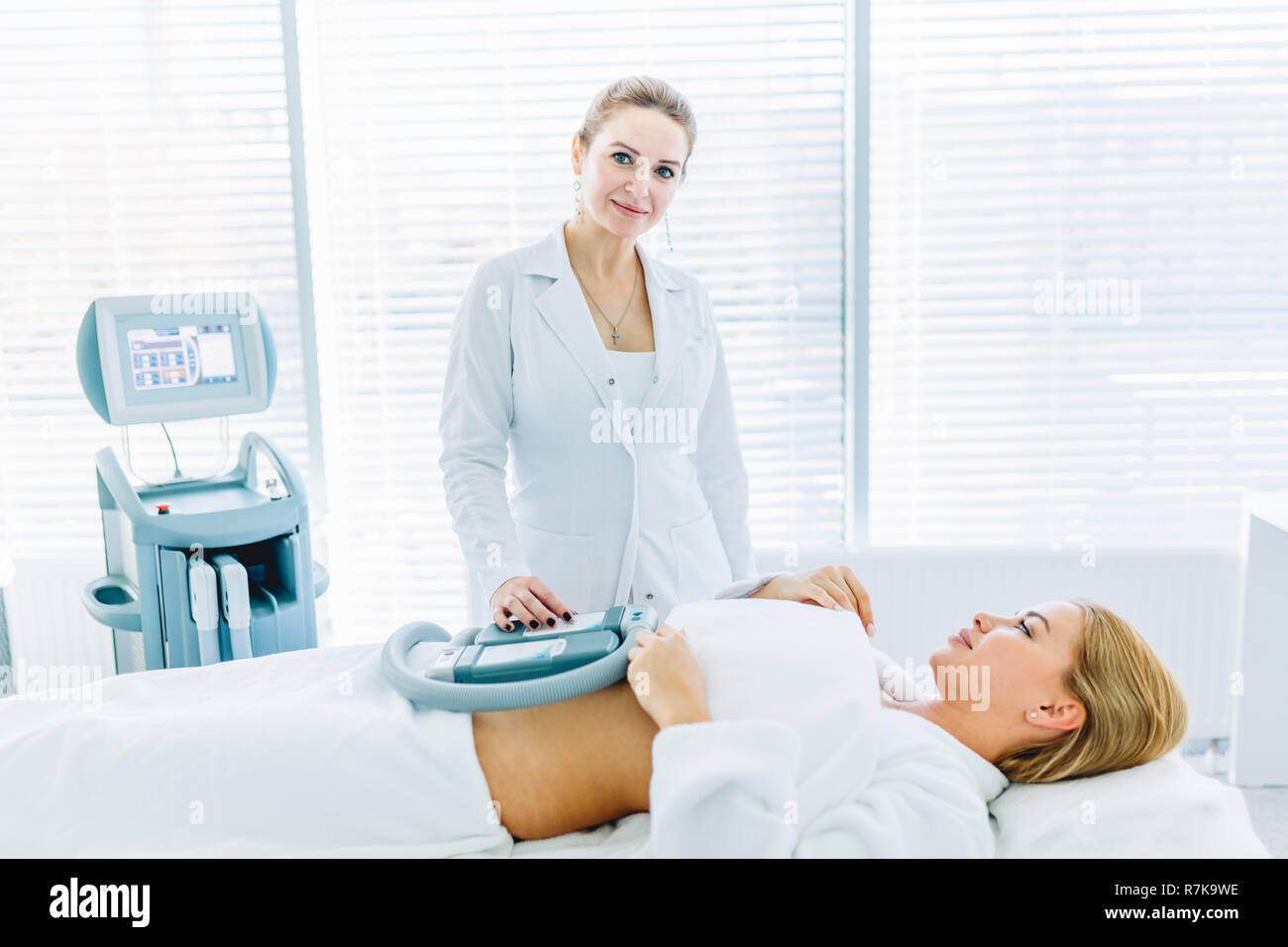 Young woman lying in medical couch with cooling elements on belly in clinic Stock Photo