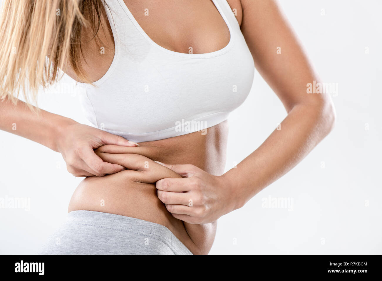 Woman pinching waist and checking her body fat. Close-up Stock Photo