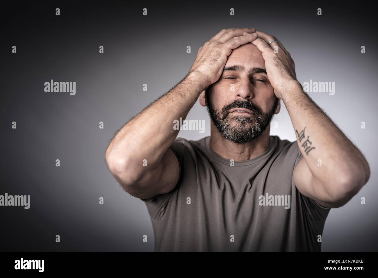 stressed man hold his head, close eyes studio portrait Stock Photo