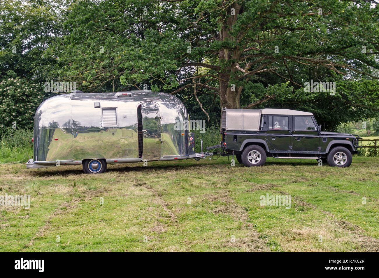 UK. Vintage Airstream caravan, towed by a Land Rover Defender 127 Stock