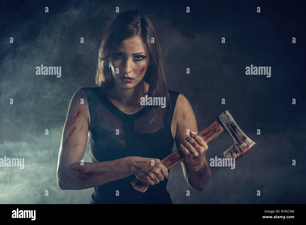 Beautiful dangerous girl with rusty axe. Looking at camera. Stock Photo