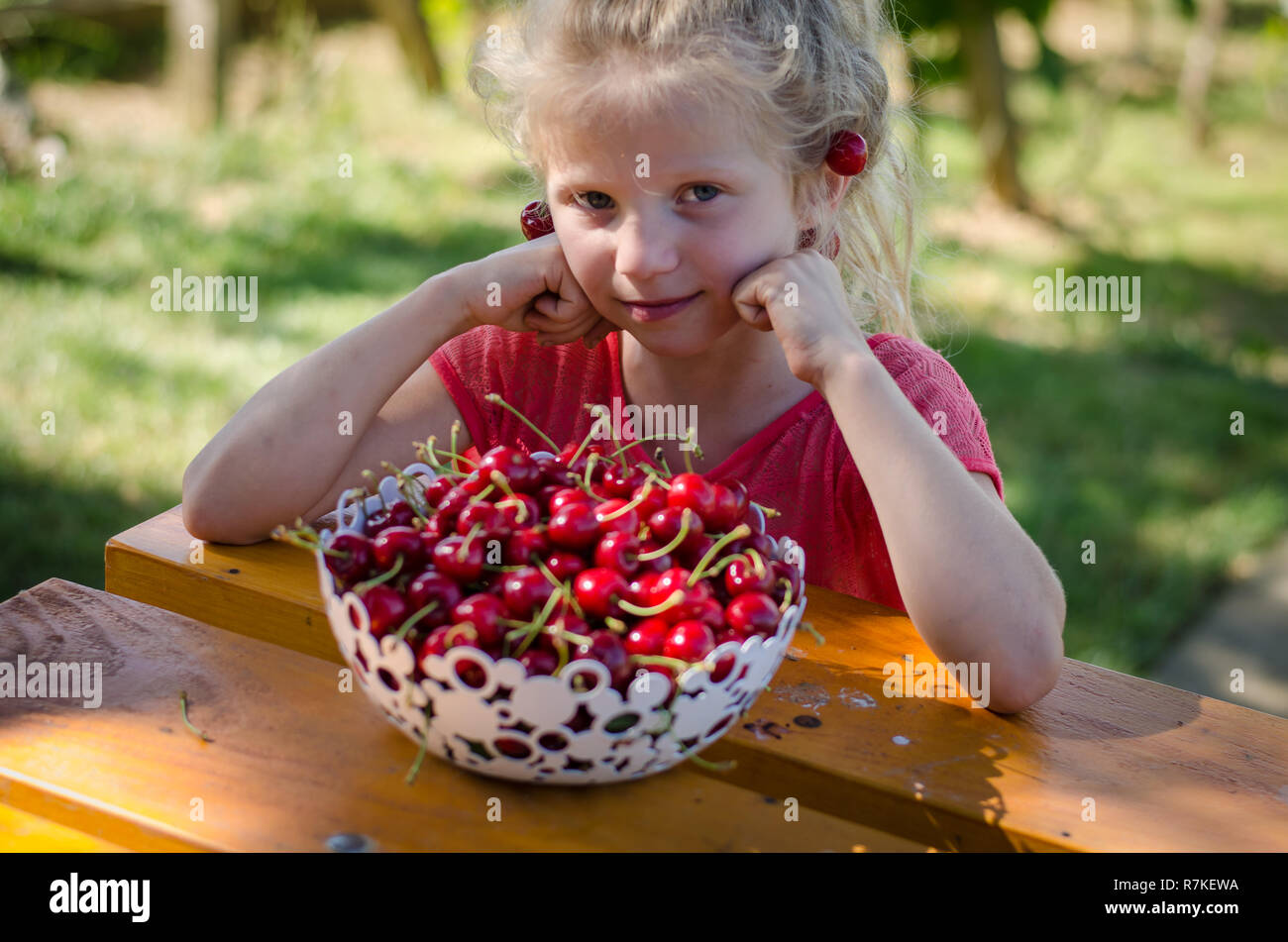adorable blond girl with cherry fruit in hands Stock Photo