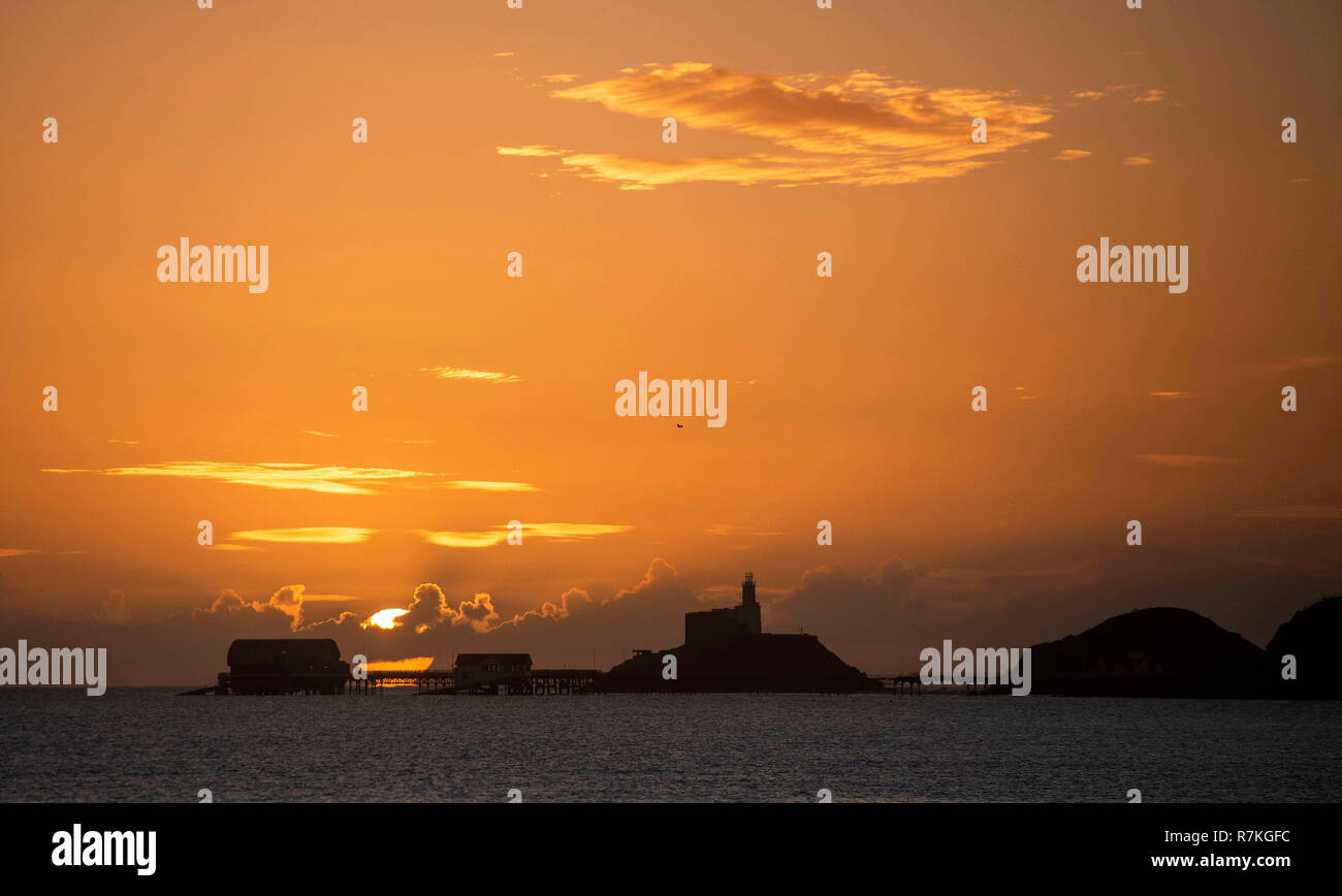 Swansea, UK. 10th Dec, 2018. UK Weather: The sun rises over the Mumbles lighthouse and Pier near Swansea today on the start of a stunning December   day. Credit: Phil Rees/Alamy Live News Stock Photo