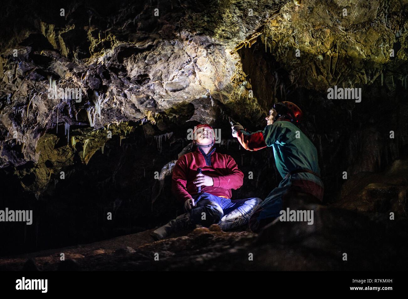 10 December 2018, North Rhine-Westphalia, Bad Wünnenberg: Cave explorers Andreas Schudelski (l) and Stefan Henscheid use their torches to illuminate the greenish-blue stalactites hanging from the ceiling of the Malachite Cathedral stalactite cave. The stalactite cave in the middle of a producing quarry has been saved for the time being. As a spokeswoman of the Paderborn district reported on 10.12.2018, an application by the quarry operator to dismantle the cave, which is under nature conservation, was rejected. Due to its enormous dimensions and the blue and green stalactites, the cave occupie Stock Photo