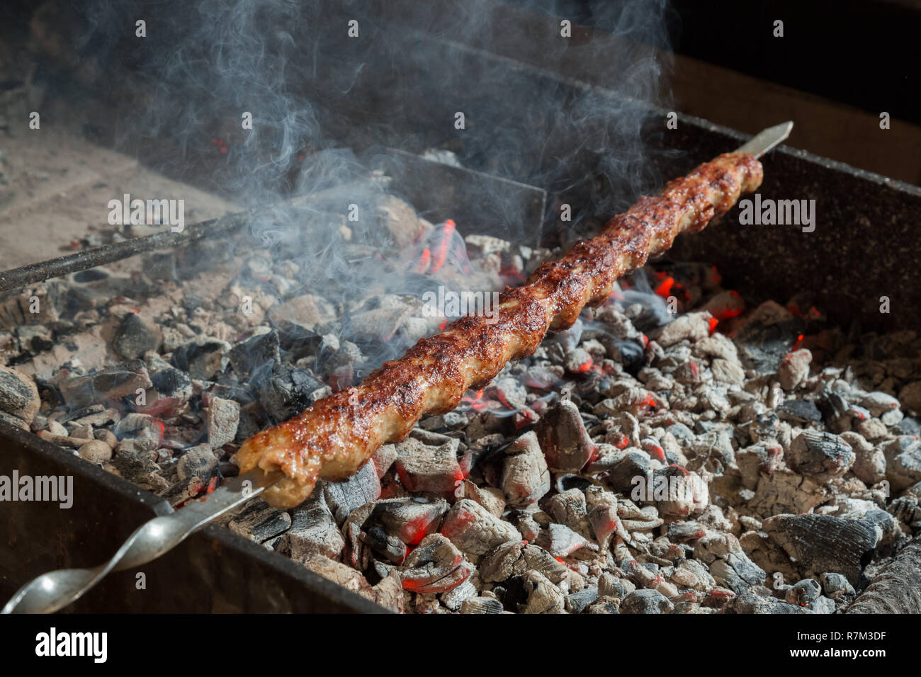 Appetizing lula kebab grilled on metal skewer. Cooking meat. Stock Photo