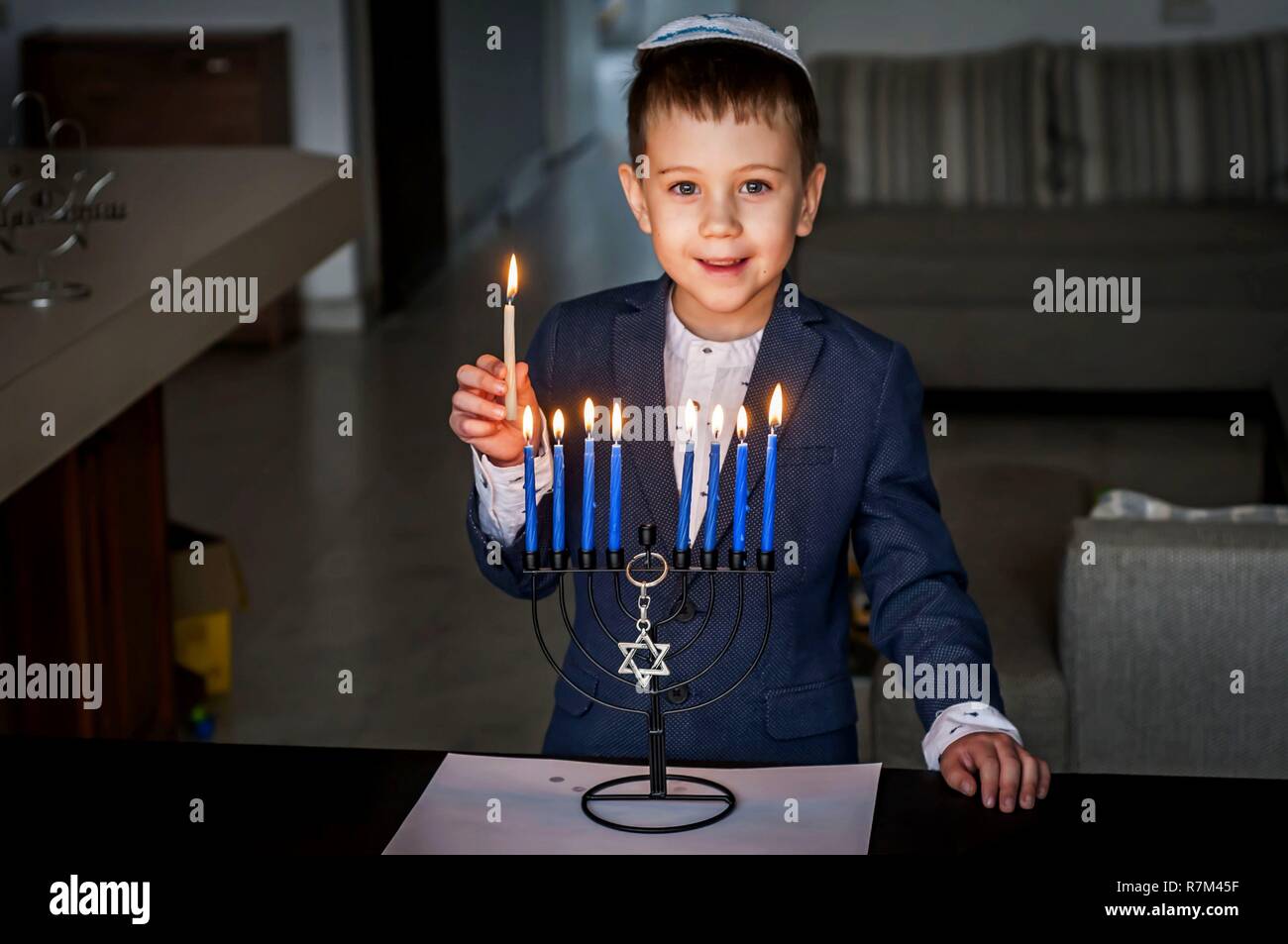 Cute Caucasian Jewish boy lighting candles on a traditional Hanukkah
