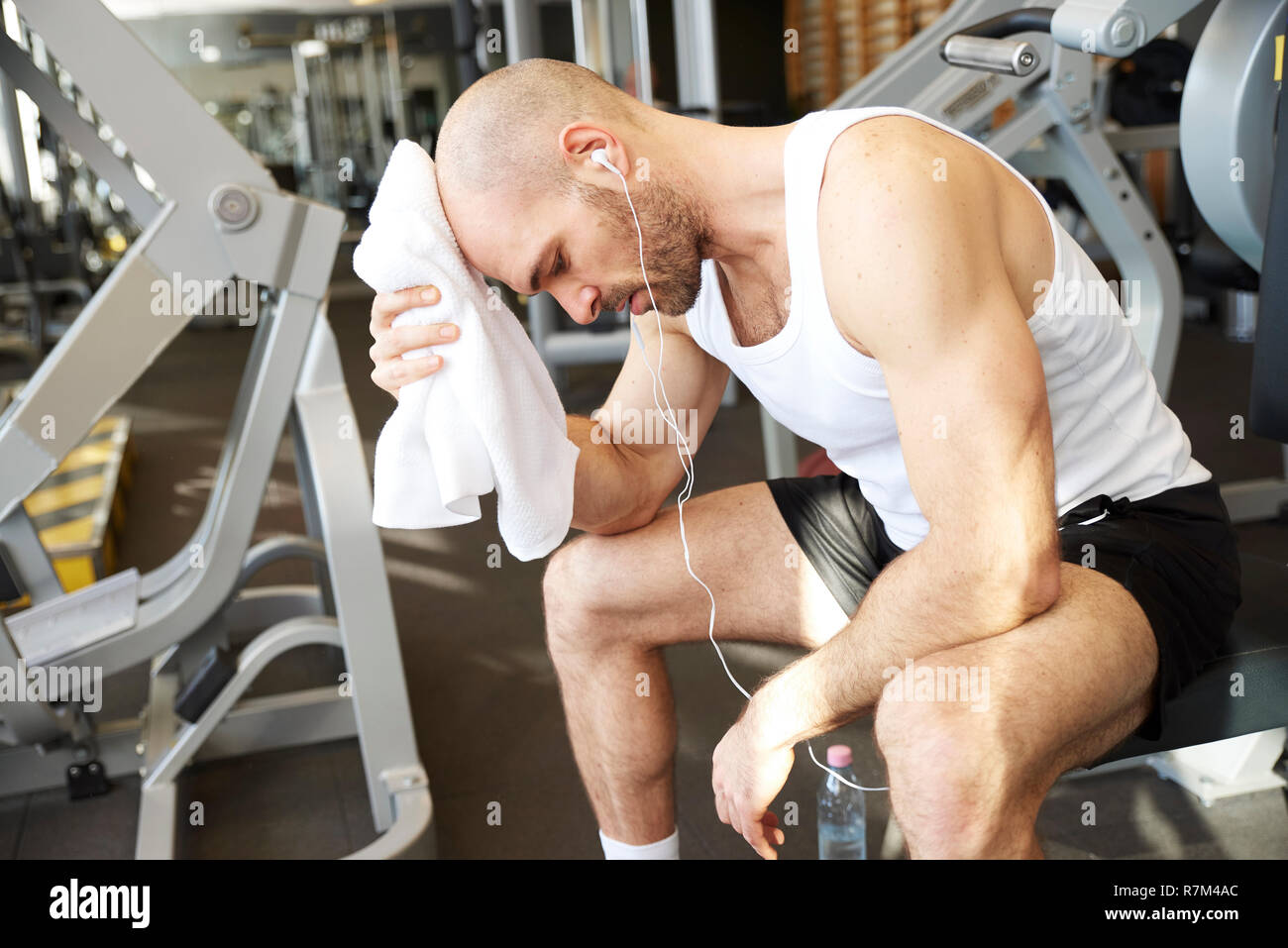 Portrait of sporty man listening music and relaxing after workout in the gym. Stock Photo