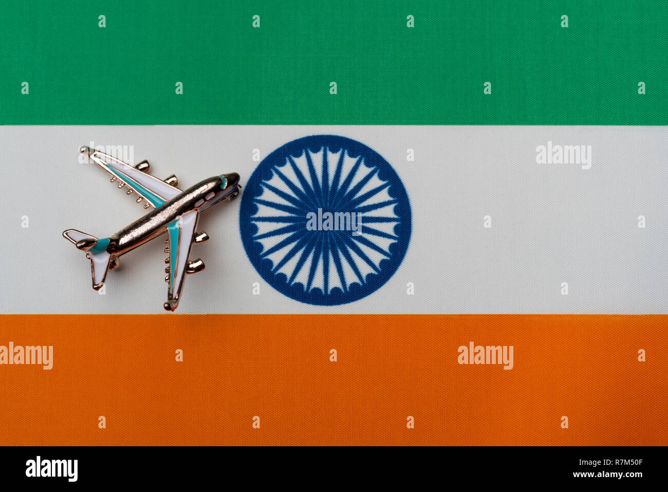 Plane over the flag of India, the concept of journey. Toy plane on the