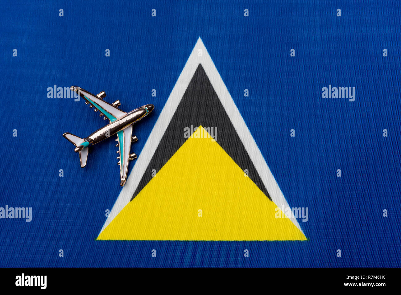 Plane over the flag of Saint Lucia, travel concept. Toy plane on the flag as a background. Stock Photo