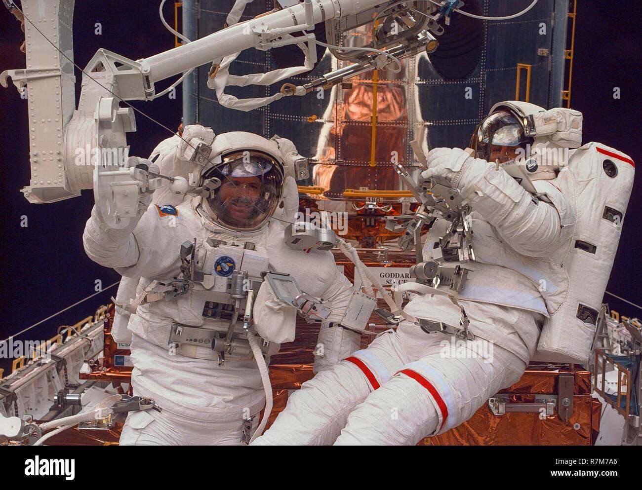 American astronauts Steven Smith, left, and Mark Lee work on maintenance and upgrading of the Hubble Space Telescope attached to the cargo by of Space Shuttle Discovery February 16, 1997 in Earth Orbit. Stock Photo