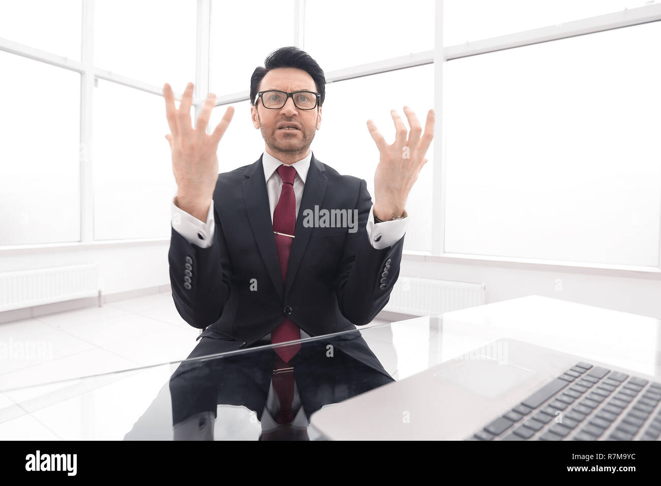 serious businessman explains something sitting at his Desk Stock Photo