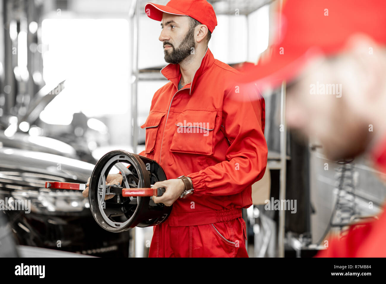 Portrait of a two auto mechanics in red uniform standing with disks for wheel alignment at the car service Stock Photo