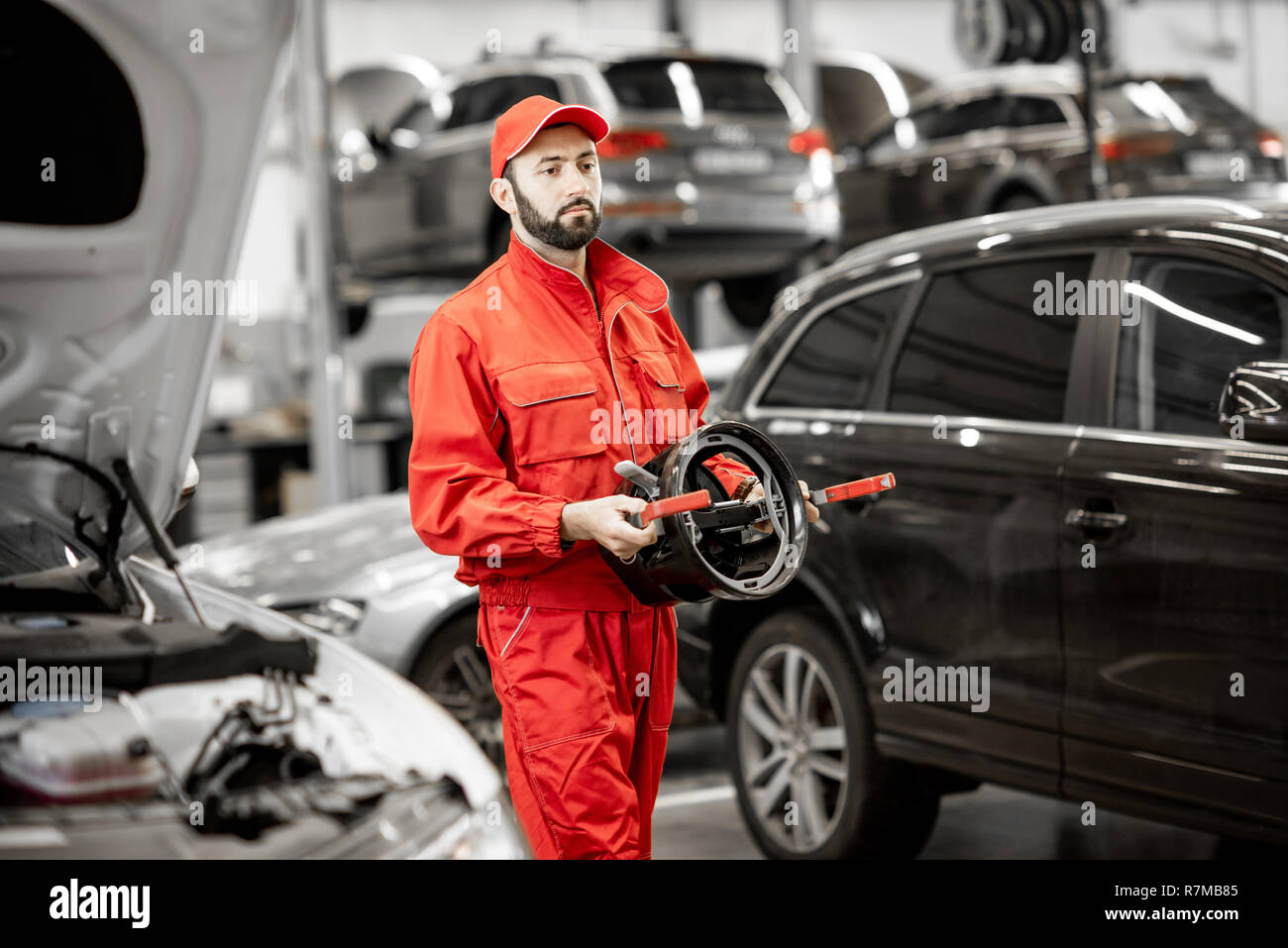 Portrait of a two auto mechanics in red uniform standing with disks for wheel alignment at the car service Stock Photo