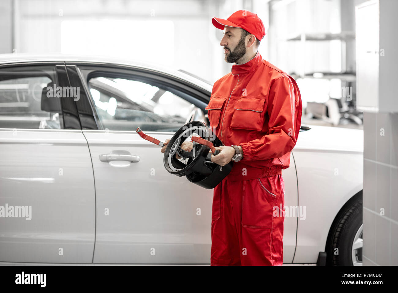 Portrait of two auto mechanics in red uniform standing with disks for wheel alignment at the car service Stock Photo
