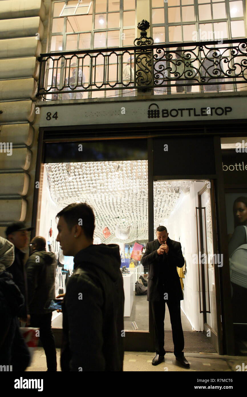 Man lighting a cigarette in doorway of Bottletop shop, Regent street, London, England, UK Stock