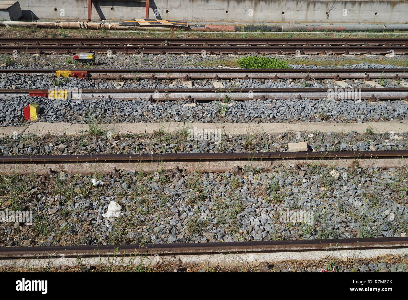 Three sets of train tracks parallel with rocks and weeds Stock Photo