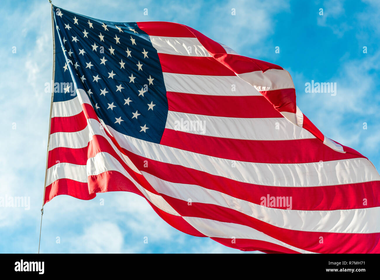 American flag waving in blue cloudy sky Stock Photo - Alamy