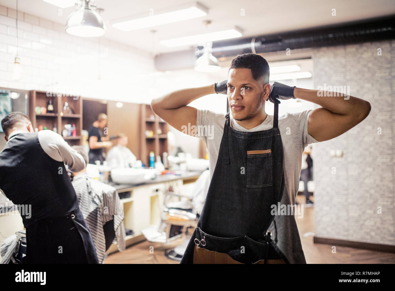Young hispanic haidresser and hairstylist standing in barber shop. Stock Photo
