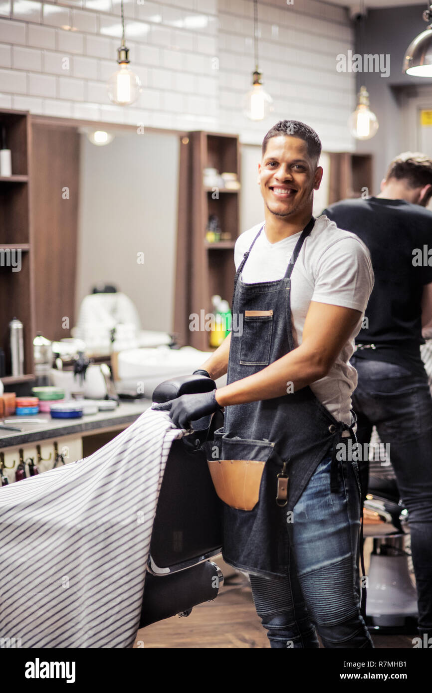 Young hispanic haidresser and hairstylist standing in barber shop. Stock Photo