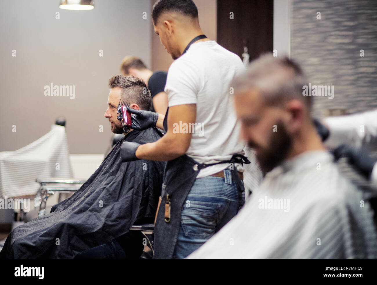 Man clients visiting haidresser and hairstylist in barber shop. Stock Photo
