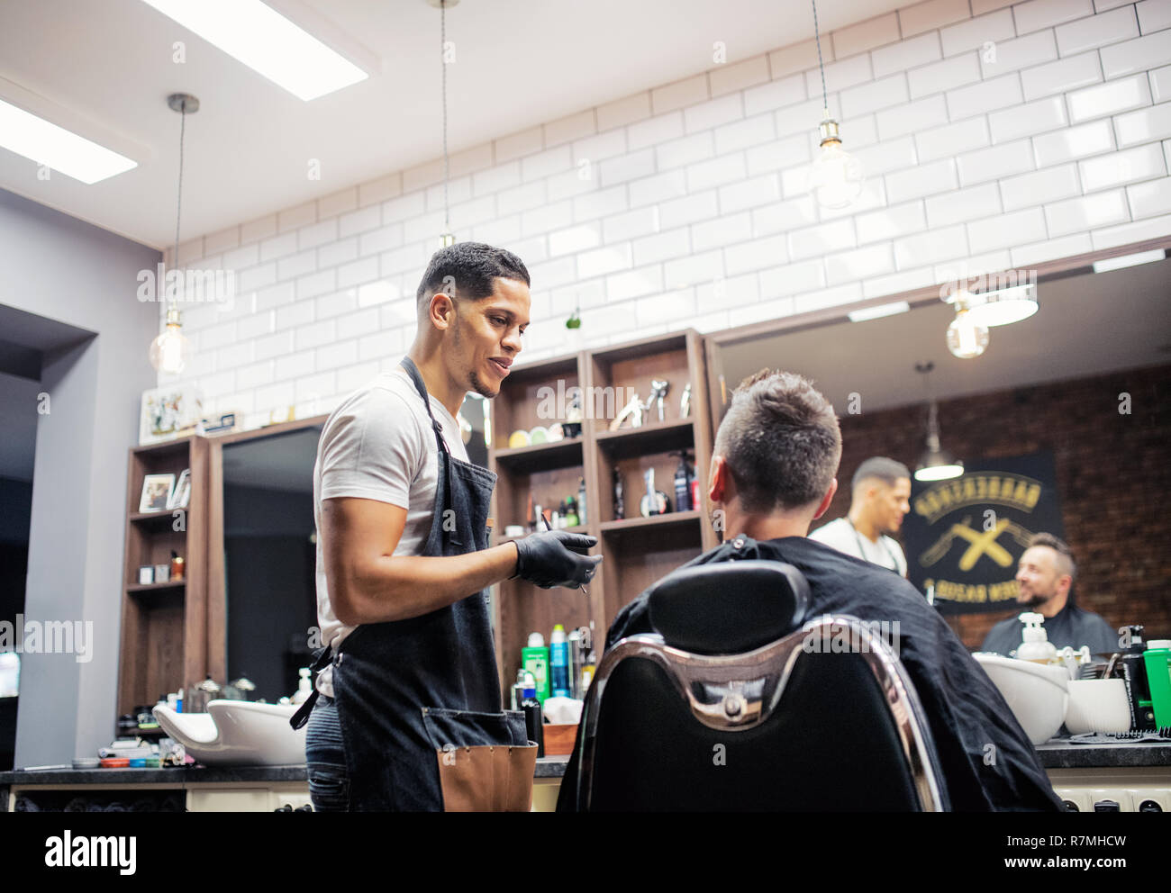 A man client talking to haidresser and hairstylist in barber shop. Stock Photo