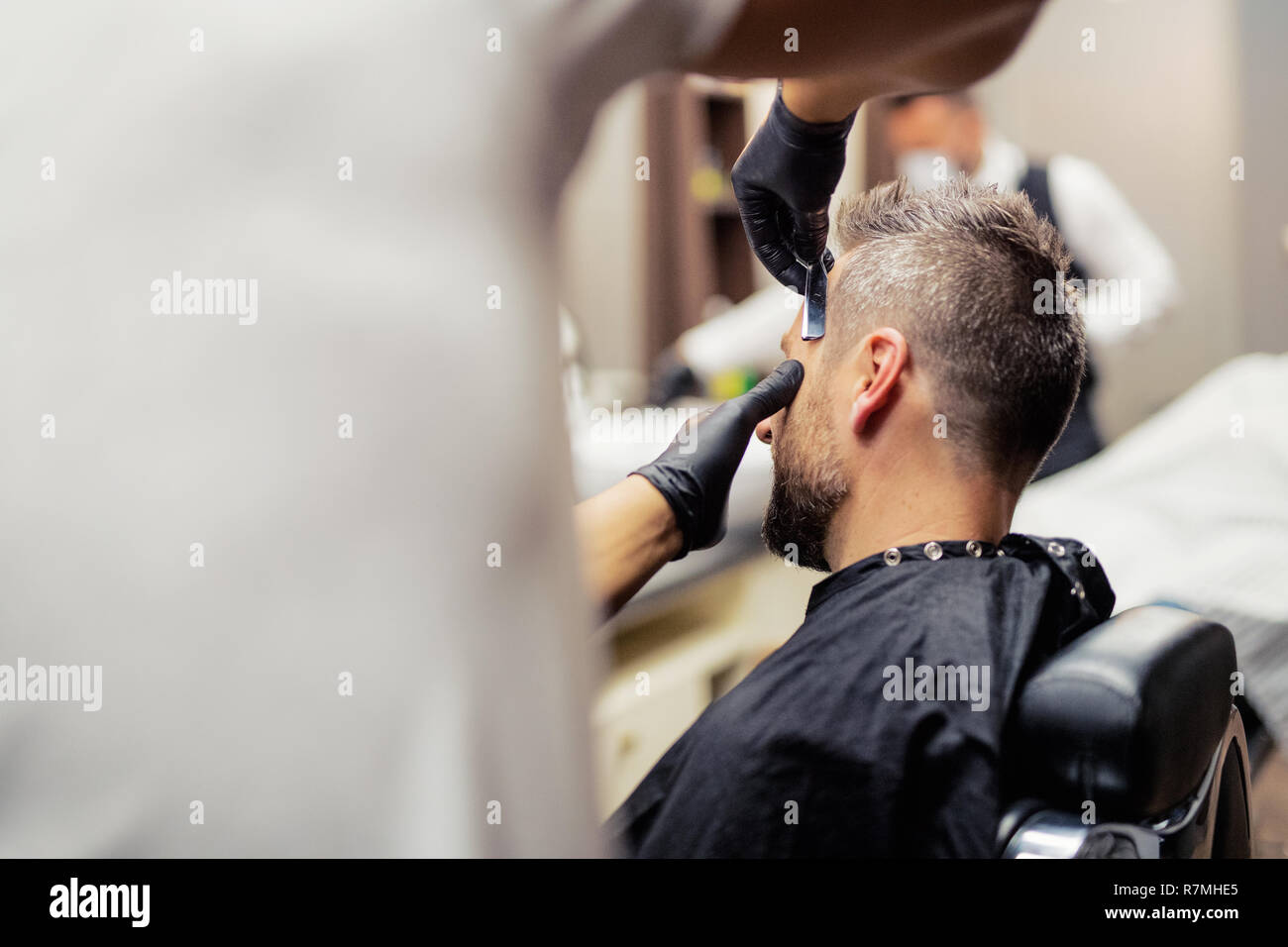 A man client visiting haidresser and hairstylist in barber shop. Stock Photo