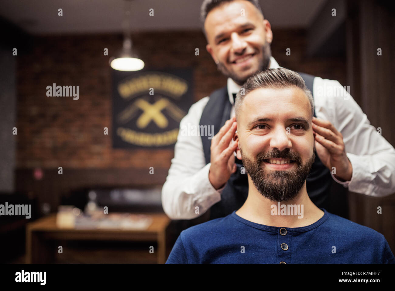 Hipster man client visiting haidresser and hairstylist in barber shop. Copy space. Stock Photo