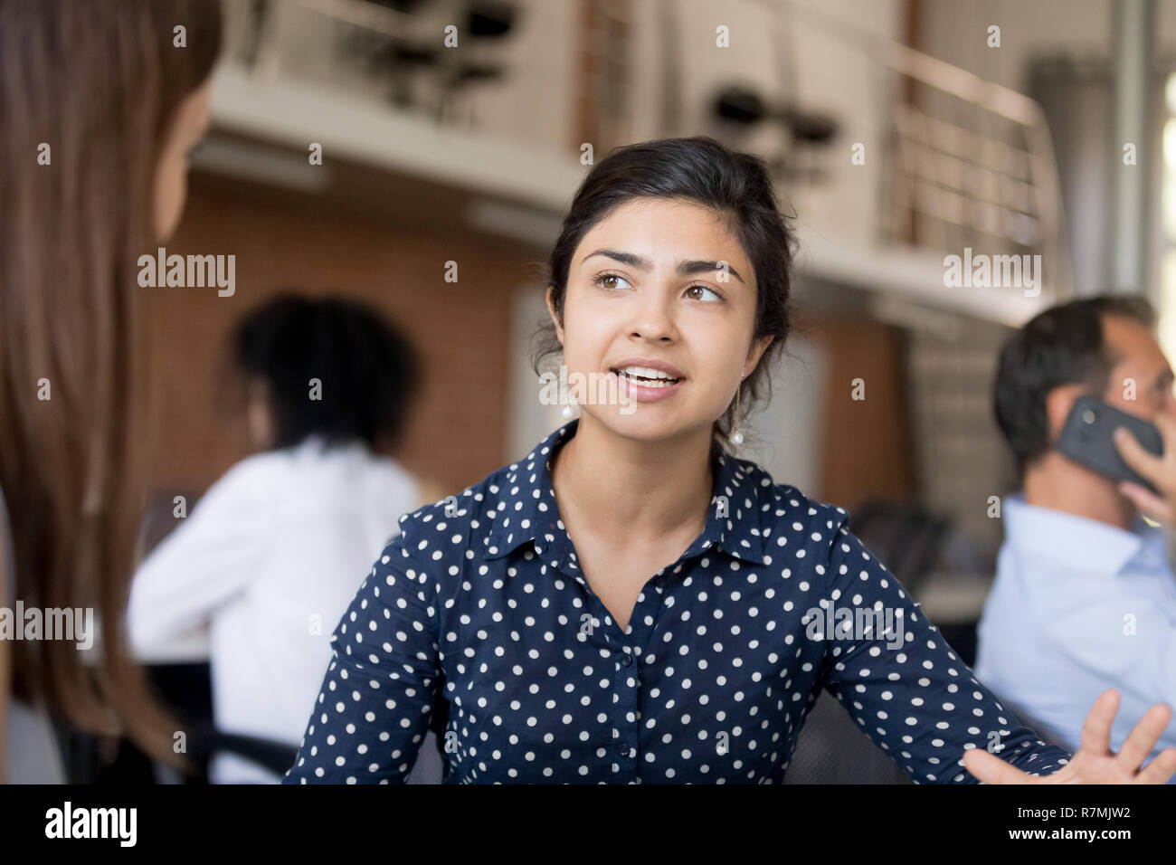 Attractive female employee talking with colleague at workplace Stock Photo