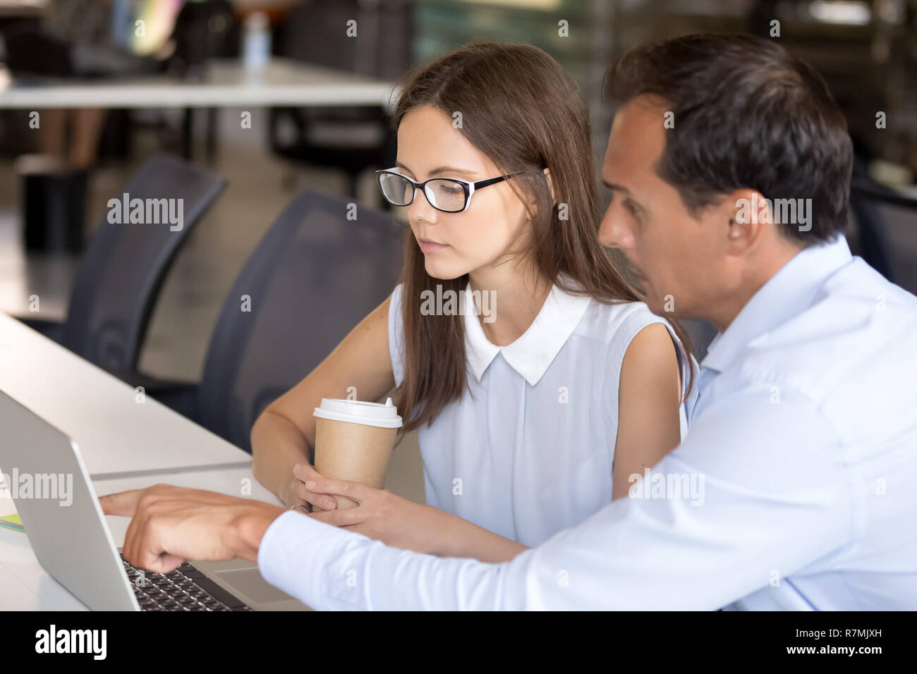 Middle aged mentor helping intern with computer work Stock Photo