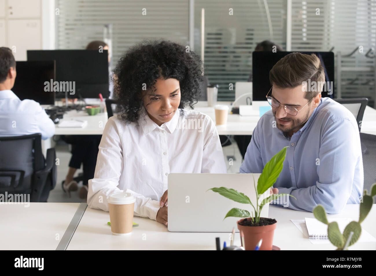 Diverse colleagues discussing computer work at workplace Stock Photo