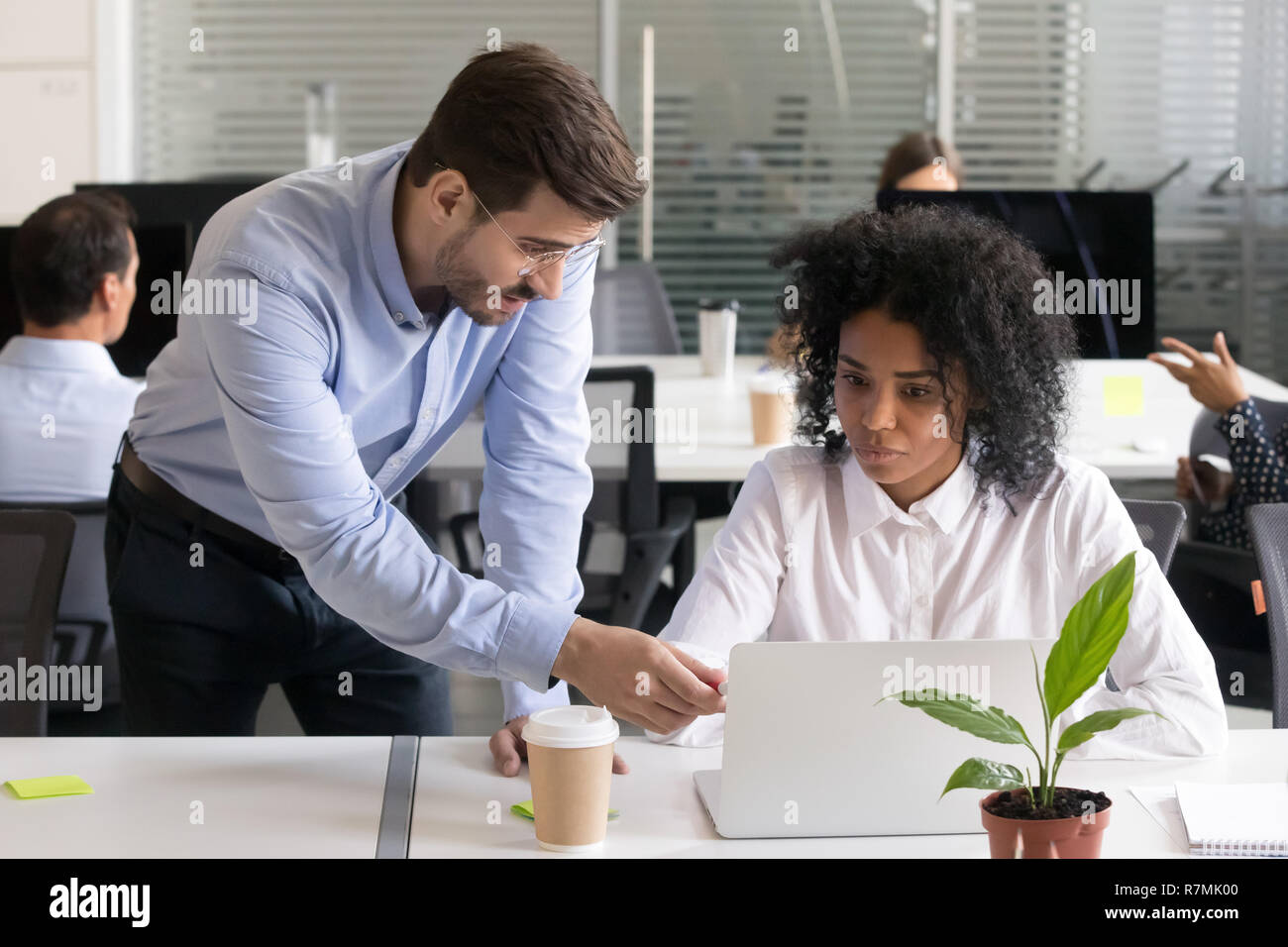 Serious verifier checking subordinate work on laptop Stock Photo