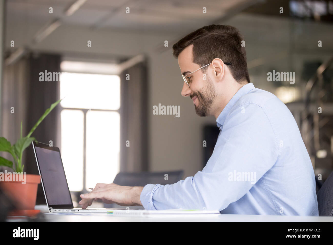 Smiling confident man in glasses using laptop, typing Stock Photo