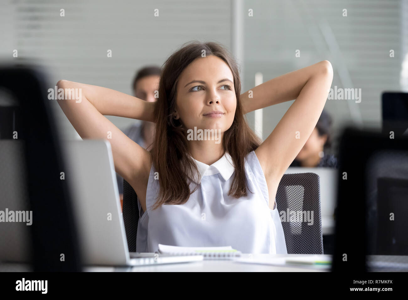 Young girl relaxing leaning back in chair, having break at workp Stock
