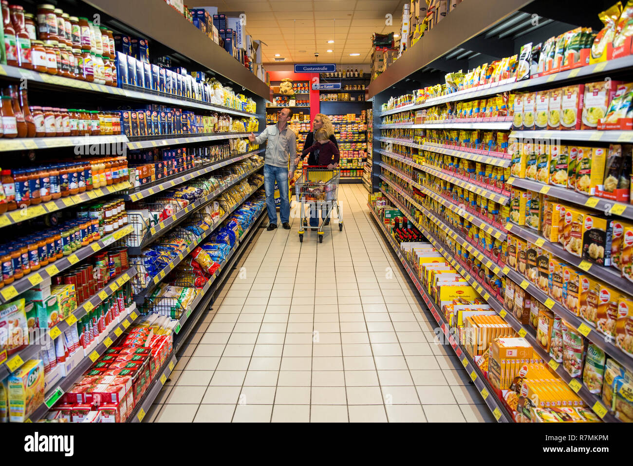 Family shopping with a shopping trolley in a supermarket, aisle with