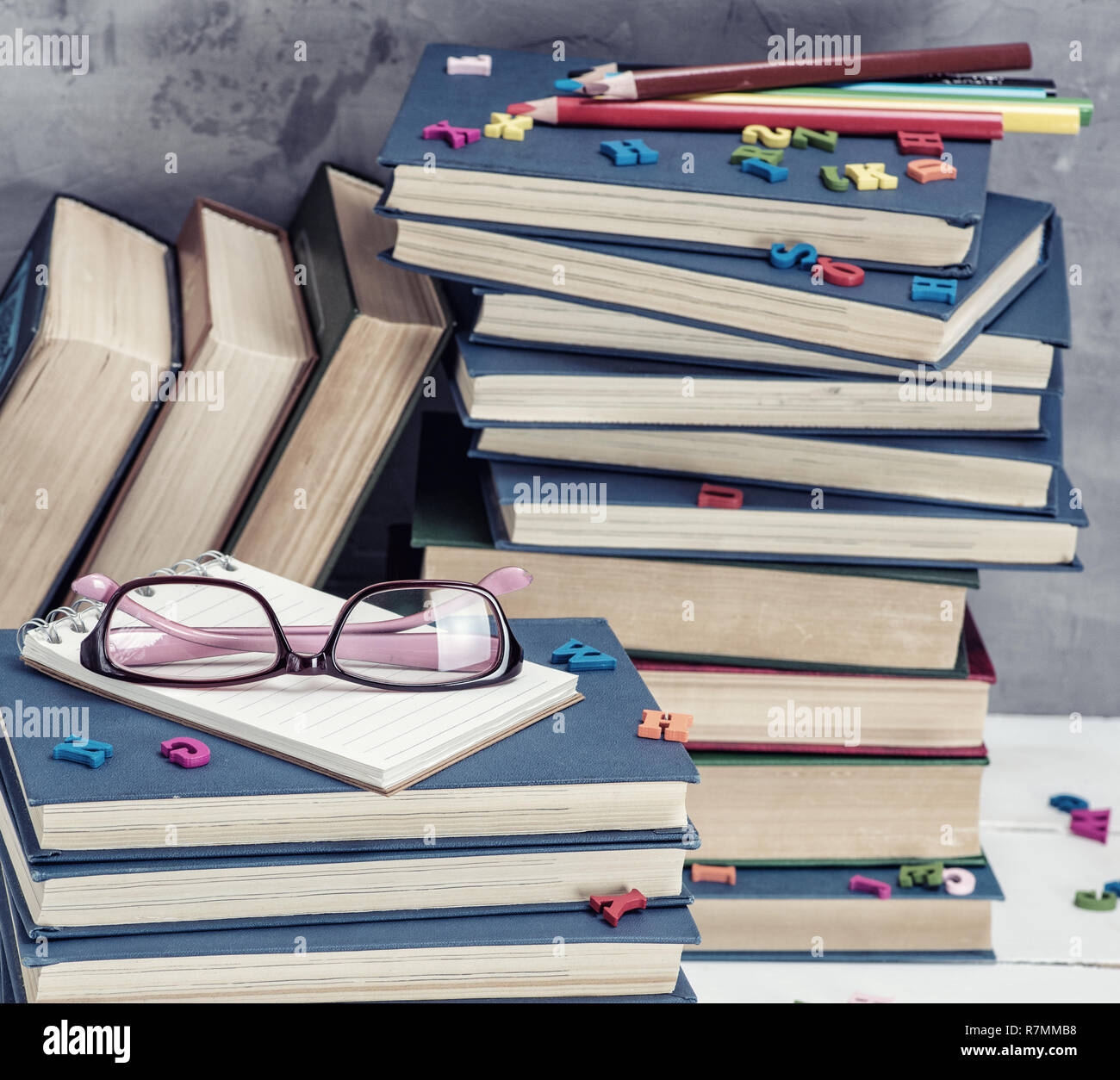 stack of books in a blue cover, pink glasses on top, close up Stock Photo