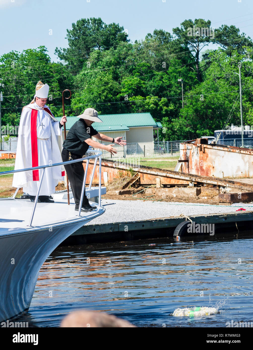 Rev. Bieu Nguyen tosses a wreath in the bayou at the Fleet Blessing as Catholic Archbishop Thomas J. Rodi watches in Bayou La Batre, Alabama. Stock Photo