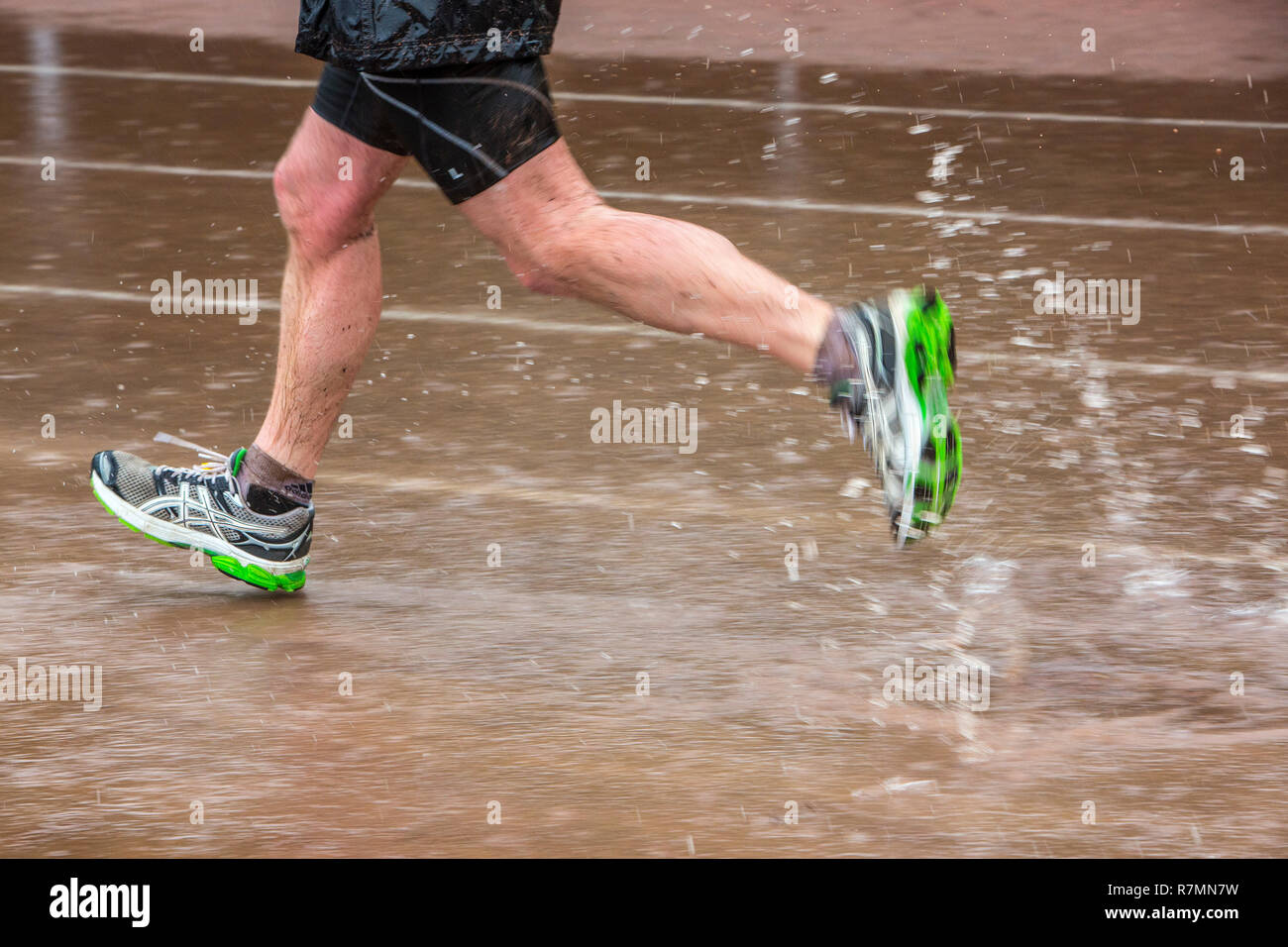 Sports field in the rain, man running through puddles of water, Germany