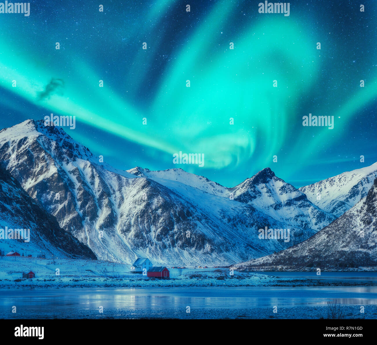 Northern lights above snowy mountains, frozen sea coast and houses in ...