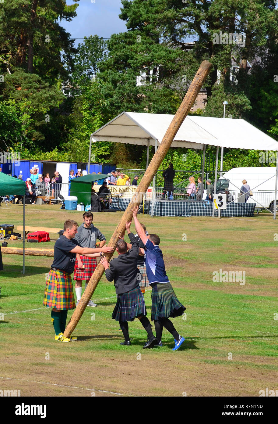 Men help to position the caber on a competitors shoulder. Stock Photo