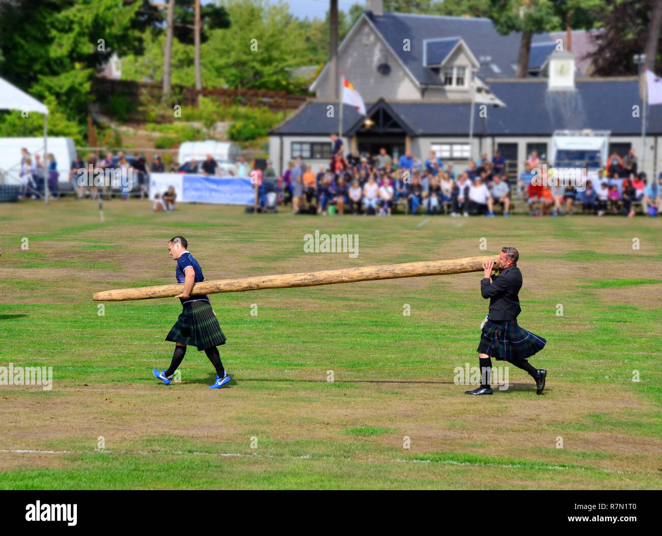 men carry the caber back to be tossed by the next competitor in the tossing the caber event at the highland games in Aboyne, Scotland Stock Photo